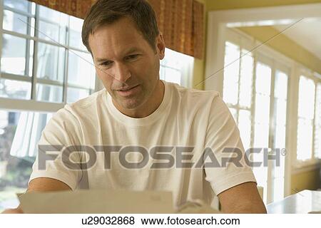 Stock Photo - Man reading letter at home. Fotosearch