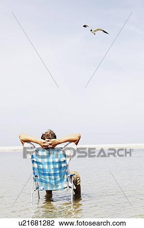 Man relaxing in lounge chair in middle of water View Large Photo Image Stock Image - Man relaxing in lounge chair in middle of water. Fotosearch