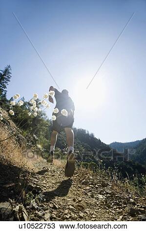 Stock Image - Man running on steep trail. Fotosearch