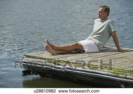 Stock Image - Man sitting on dock. Fotosearch