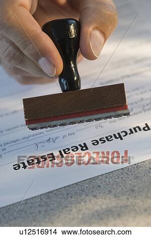 Picture - Man stamping “foreclosure” on mortgage form. Fotosearch