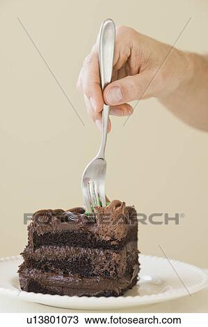 Stock Image - Man sticking fork in cake slice. Fotosearch