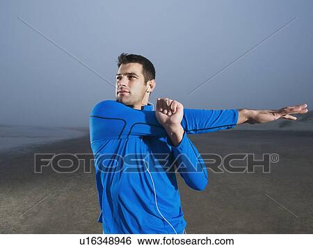 Stock Photograph - Man stretching on beach. Fotosearch