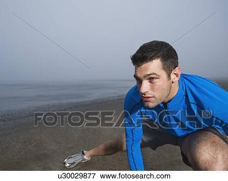 Stock Photo - Man stretching on foggy beach. Fotosearch