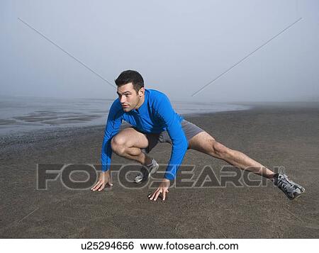 Stock Photograph - Man stretching on foggy beach. Fotosearch