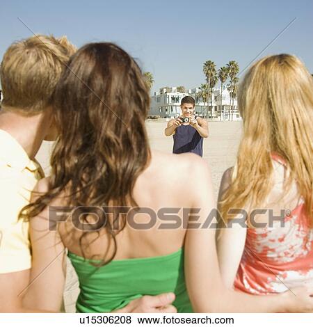 Stock Photo - Man taking photograph of friends. Fotosearch