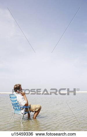 Man talking on cell phone in middle of water View Large Photo Image Stock Photograph - Man talking on cell phone in middle of water. Fotosearch