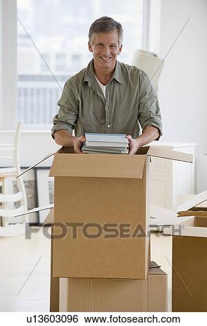 Stock Photograph - Man unpacking moving boxes. Fotosearch