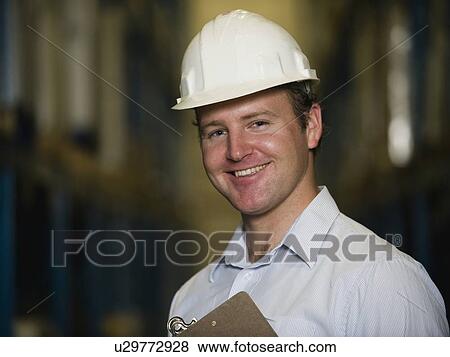 Stock Photo - Man wearing hard hat and holding clipboard. Fotosearch