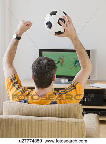 Man with soccer ball cheering at television View Large Photo Image Stock Photo - Man with soccer ball cheering at television. Fotosearch