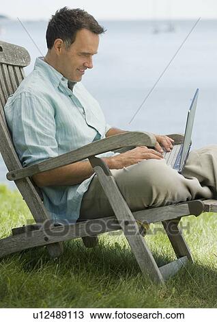 Man working on laptop outdoors View Large Photo Image Stock Image - Man working on laptop outdoors. Fotosearch