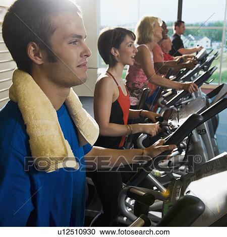 Stock Image - Men and women on elliptical trainers. Fotosearch