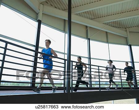 Stock Image - Men and women running on indoor track. Fotosearch