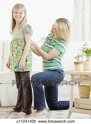 Stock Photography - Mother adjusting daughter’s shirt. Fotosearch