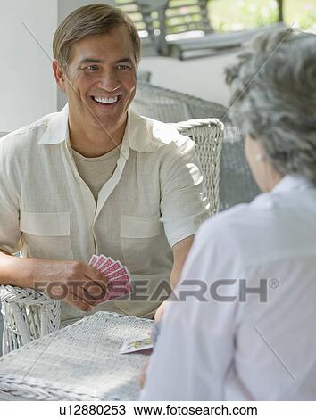 Stock Image - Mother and adult son playing card game on porch. Fotosearch