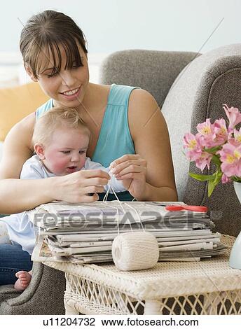 Stock Image - Mother and baby bundling newspapers. Fotosearch