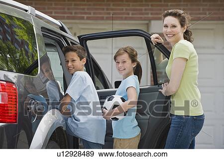 Stock Photo - Mother and children getting into car with soccer ball. Fotosearch