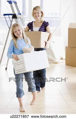 Stock Photo - Mother and daughter carrying moving boxes. Fotosearch