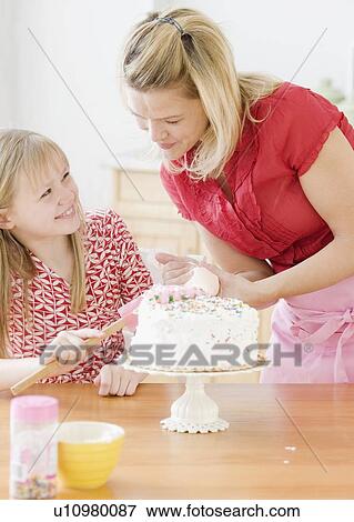 Stock Photo - Mother and daughter decorating birthday cake. Fotosearch