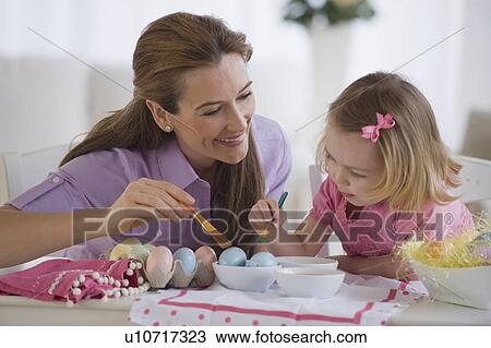Stock Image - Mother and daughter decorating eggs. Fotosearch