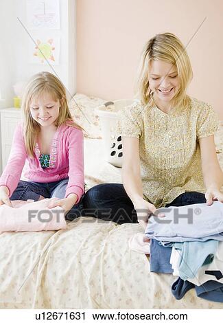Mother and daughter folding clothing View Large Photo Image Stock Image - Mother and daughter folding clothing. Fotosearch