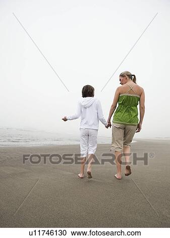 Mother and daughter holding hands and walking on beach View Large Photo Image Stock Image - Mother and daughter holding hands and walking on beach. Fotosearch