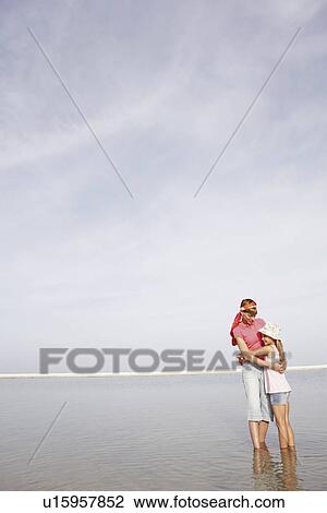 Stock Image - Mother and daughter hugging on beach. Fotosearch