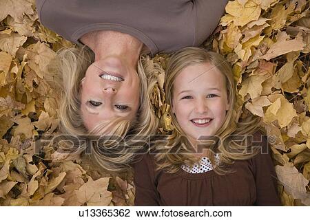 Mother and daughter laying in autumn leaves View Large Photo Image Stock Image - Mother and daughter laying in autumn leaves. Fotosearch