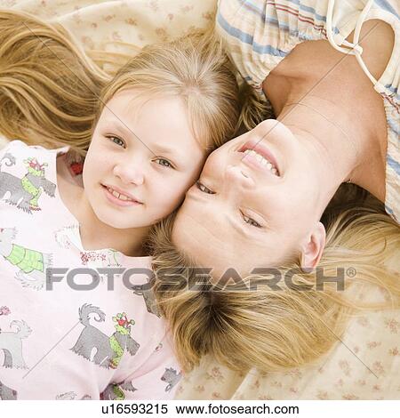 Stock Photography - Mother and daughter laying on bed. Fotosearch