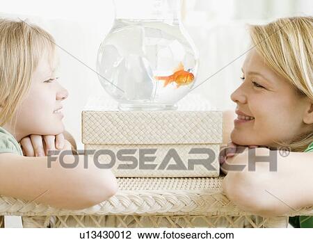 Mother and daughter looking at fish in bowl View Large Photo Image Stock Image - Mother and daughter looking at fish in bowl. Fotosearch