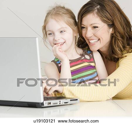Mother and daughter looking at laptop View Large Photo Image Stock Image - Mother and daughter looking at laptop. Fotosearch