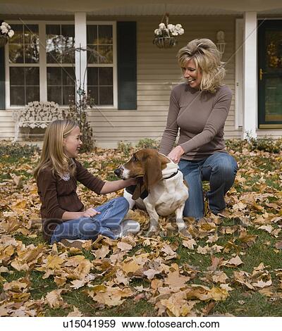 Mother and daughter petting dog outdoors View Large Photo Image Stock Photo - Mother and daughter petting dog outdoors. Fotosearch