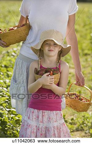 Stock Image - Mother and daughter picking fresh strawberries. Fotosearch