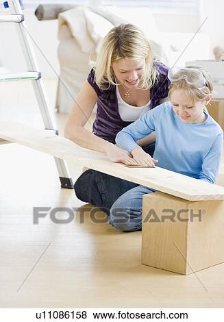 Stock Photo - Mother and daughter sanding wood plank. Fotosearch