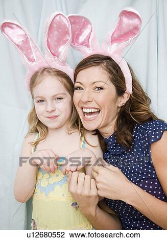 Stock Image - Mother and daughter wearing rabbit ears. Fotosearch