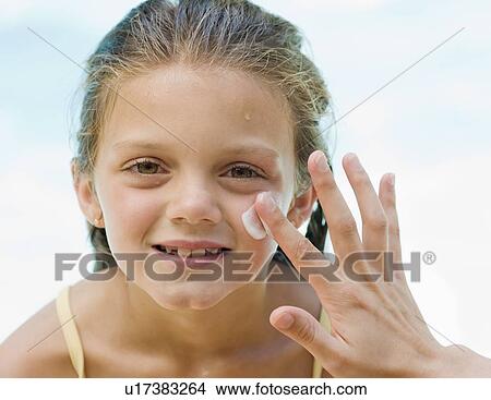 Picture - Mother applying sunscreen to daughter’s face. Fotosearch