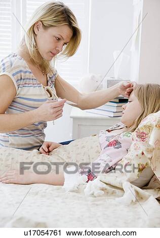 Stock Image - Mother checking daughter’s temperature. Fotosearch