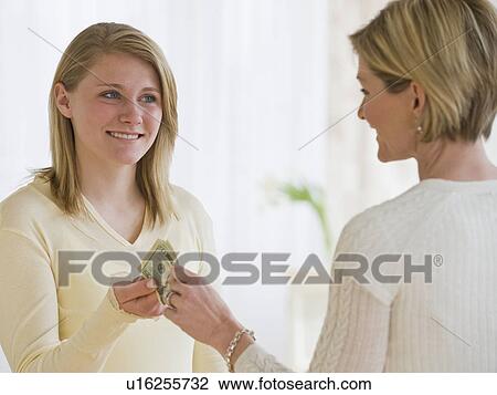 Stock Image - Mother giving money to teenaged daughter. Fotosearch