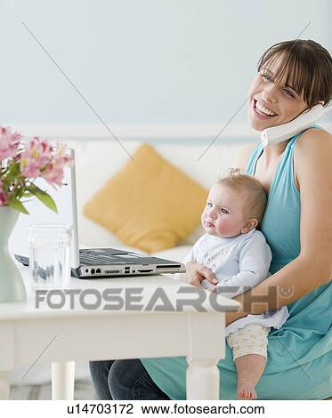 Mother holding baby and working at home View Large Photo Image Stock Image - Mother holding baby and working at home. Fotosearch