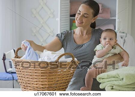 Mother holding baby son and sorting laundry View Large Photo Image Stock Image - Mother holding baby son and sorting laundry. Fotosearch