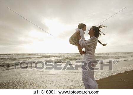 Stock Image - Mother holding son at beach. Fotosearch