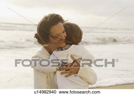 Stock Image - Mother hugging child at beach. Fotosearch