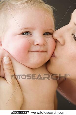Stock Photo - Mother kissing baby’s cheek. Fotosearch