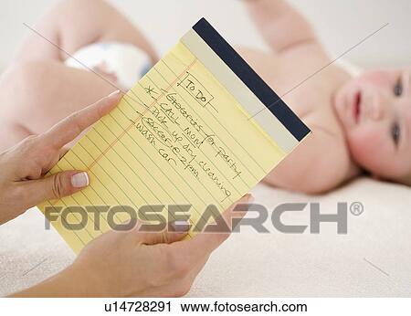 Mother looking at To Do list in front of baby View Large Photo Image Stock Image - Mother looking at To Do list in front of baby. Fotosearch
