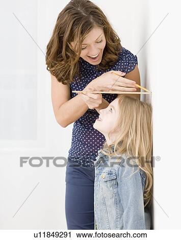 Mother measuring daughter’s height View Large Photo Image Stock Image - Mother measuring daughter’s height. Fotosearch