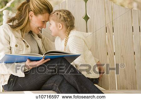 Mother reading to daughter on porch swing View Large Photo Image Stock Photo - Mother reading to daughter on porch swing. Fotosearch
