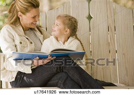 Stock Photograph - Mother reading to daughter on porch swing. Fotosearch