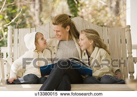 Mother reading to daughters on porch swing View Large Photo Image Stock Photography - Mother reading to daughters on porch swing. Fotosearch