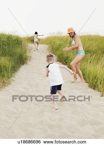 Stock Photograph - Mother running on beach with daughter and son. Fotosearch