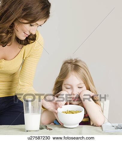 Stock Image - Mother serving vegetables to daughter. Fotosearch